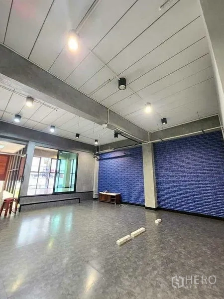Office Space for rent or sale in Bueng Kum, Bangkok - Large multifunction room with grey vinyl flooring, blue accent wall, wide windows and track lighting.