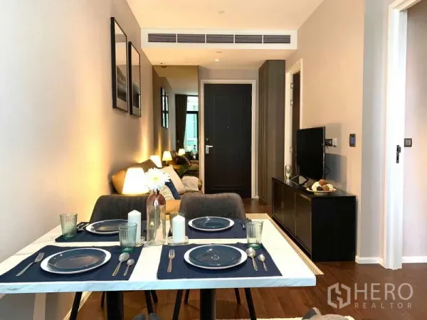 Condominium for rent in Watthana, Bangkok - Dining table set for four in an open-plan space leading to the living room.