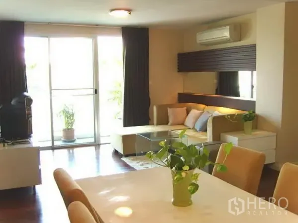 Condominium for rent in Watthana, Bangkok - Bright living room with L-shaped sofa, glass coffee table and sliding doors to the balcony.