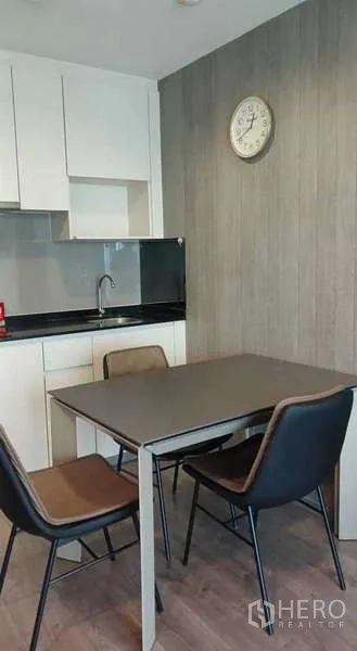Condominium for rent or sale - Compact kitchenette with white cabinets, black countertop and dining table with chairs.