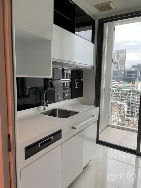 คอนโด ให้เช่าหรือขายในPhra Khanong, Bangkok - ครัวสีขาวทันสมัย เปิดออกสู่ระเบียงชมวิวกรุงเทพฯ