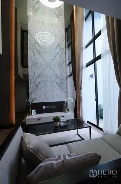 คอนโด ให้เช่าในPathum Wan, Bangkok - ผนังลายหินอ่อนและหน้าต่างสูงพร้อมโคมไฟในโซนนั่งเล่น