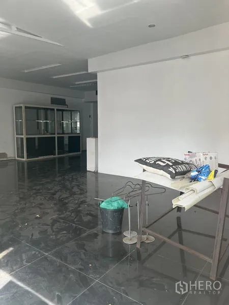 零售空间 出租在Watthana, Bangkok - 店内近景，陈设与清洁用品摆放在亮面地砖上。