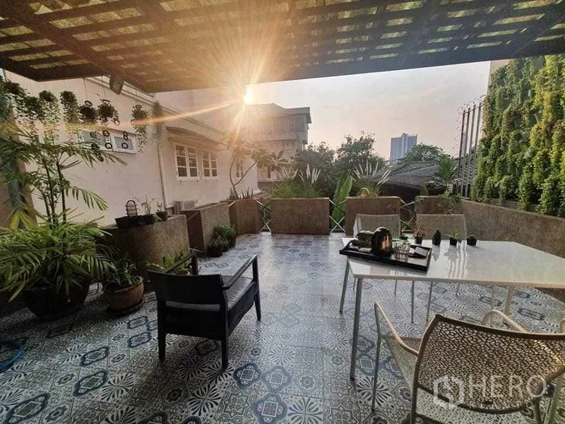 Townhouse for rent or sale in Bang Kho Laem, Bangkok - Rooftop-style terrace at sunset with pergola shade, potted plants and city outlook.