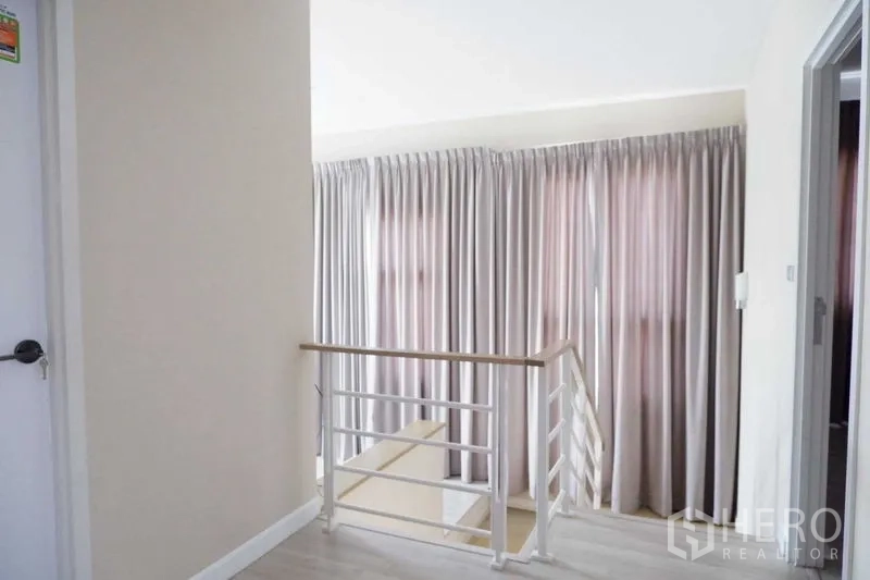 บ้าน ขายในLat Krabang, Bangkok - โถงทางเดินชั้นบน ราวบันไดเหล็กและผ้าม่านสูงรับแสงธรรมชาติ