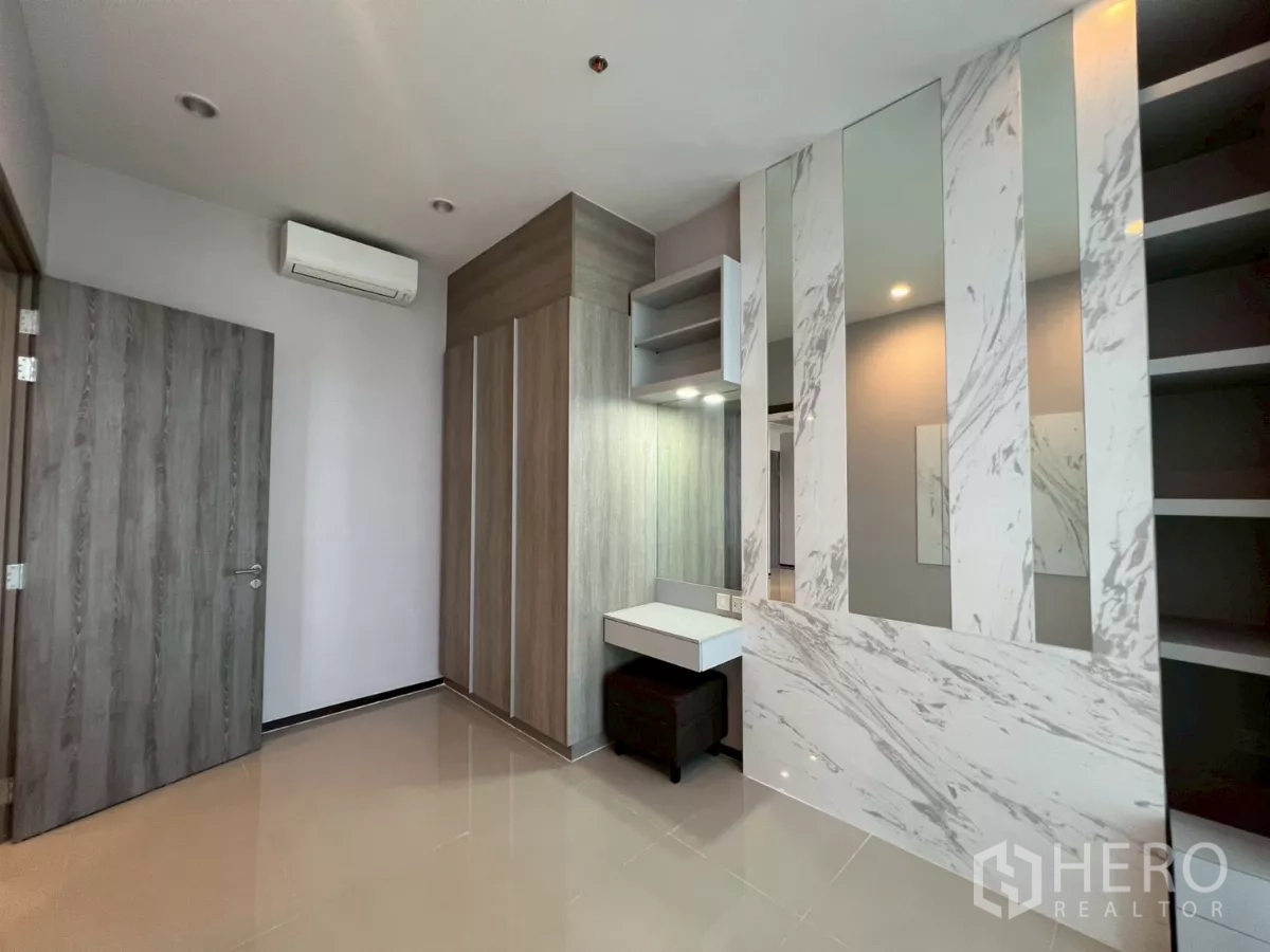 Condominium for rent in Phra Khanong, Bangkok - Second bedroom with wardrobe, vanity desk, and marble accent panels.