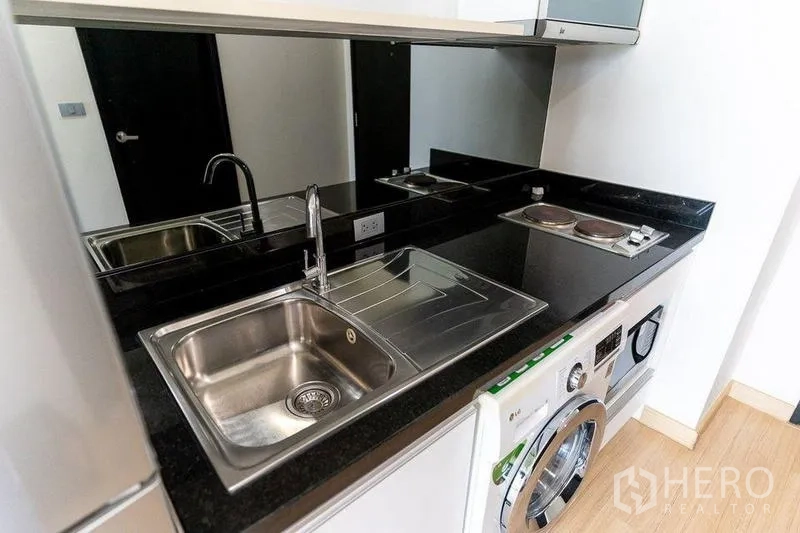 Condominium for rent - Compact kitchen with black granite countertop, sink, mirrored backsplash and under-counter washer.