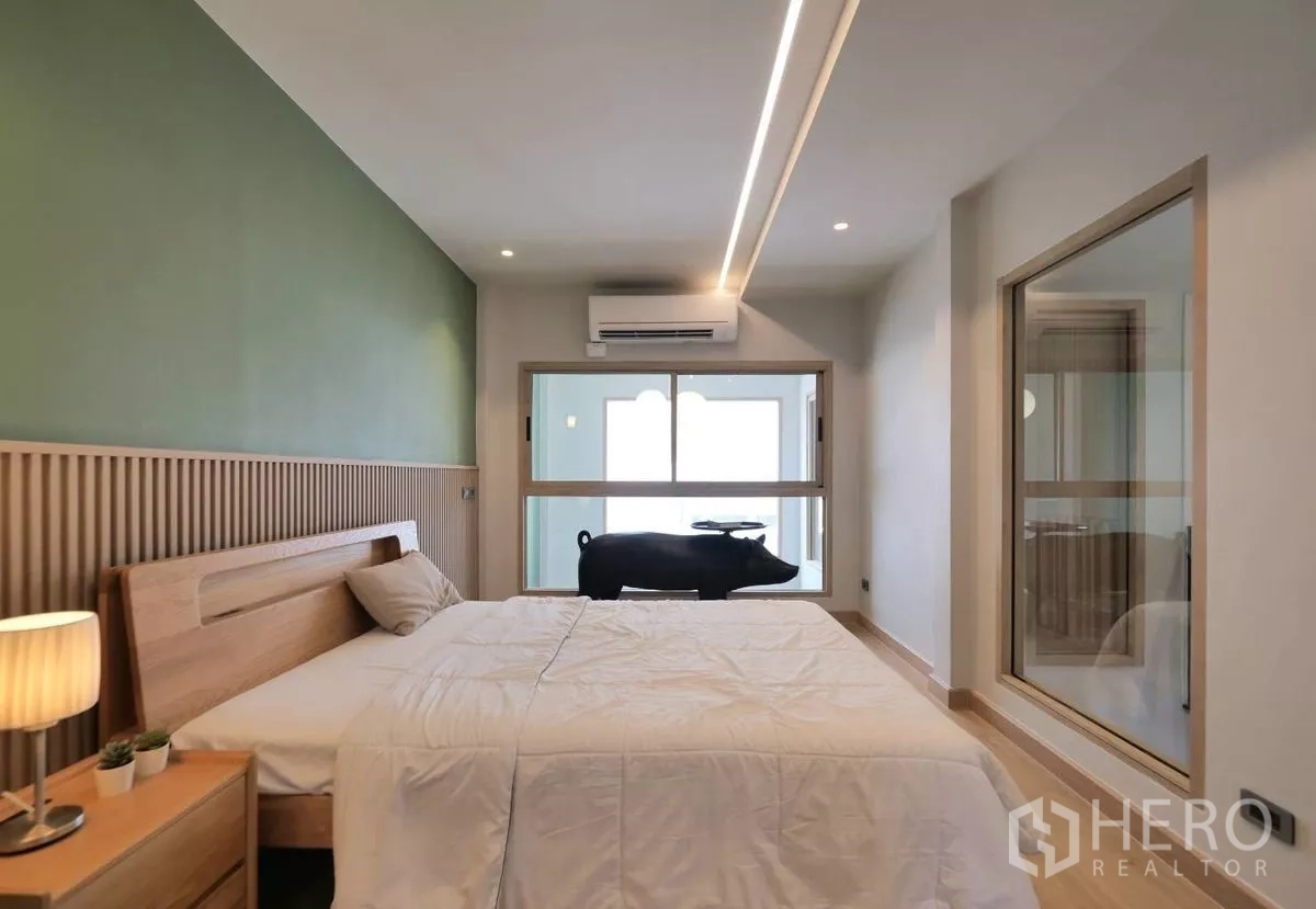 ทาวน์เฮาส์ ให้เช่าในWatthana, Bangkok - ห้องนอนอบอุ่น ผนังสีเขียว หัวเตียงไม้ และหน้าต่างภายใน