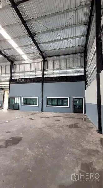 โรงงาน ให้เช่าหรือขายในPhanat Nikhom, Chon Buri - ผนังด้านในมีหน้าต่างและประตู ใต้โครงหลังคาเหล็กสูง