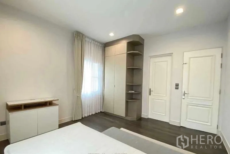Detached House for rent in Bang Khen, Bangkok - Bedroom with built-in wardrobe, open shelves and bright white walls.