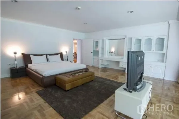 อพาร์ทเมนท์ ให้เช่าในRatchathewi, Bangkok - ห้องนอนใหญ่กว้างพร้อมตู้บิลท์อินสีขาว โต๊ะเครื่องแป้ง ที่วางทีวี และพื้นปาร์เกต์เงางาม