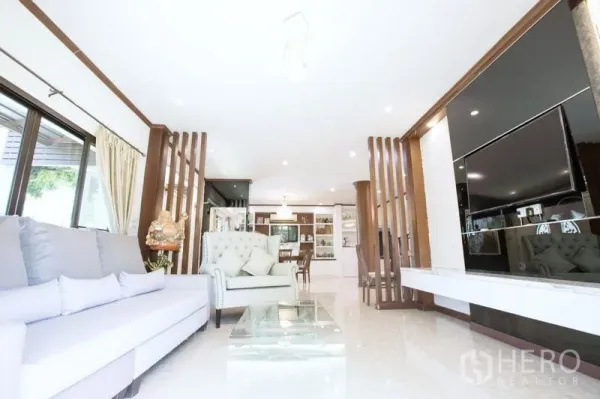 บ้าน ขายในLat Krabang, Bangkok - โถงรับแขกแบบโอเพ่นพร้อมผนังทีวีบิวท์อิน งานไม้ และมุมมองไปยังโซนทานข้าวและครัว