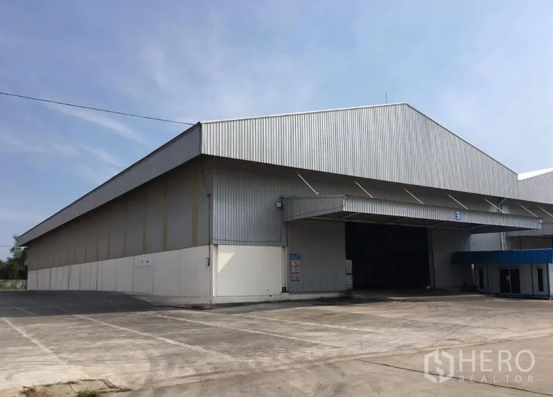 Warehouse for rent in Mueang Samut Songkhram, Samut Songkhram - Angled exterior of the warehouse showing extended canopy, spacious driveway and loading entrance.