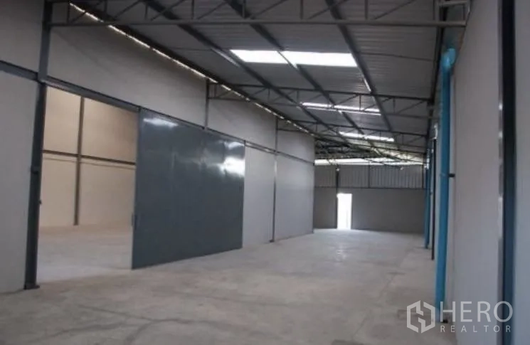 Warehouse for rent in Bang Phli, Samut Prakan - Warehouse interior featuring large sliding steel doors and high roof trusses.