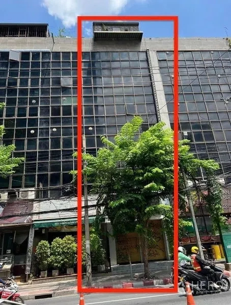 Shophouse for rent in Bang Rak, Bangkok - Street-front shophouse within a glass-clad commercial block in Bang Rak, with trees and a ground-floor shopfront.