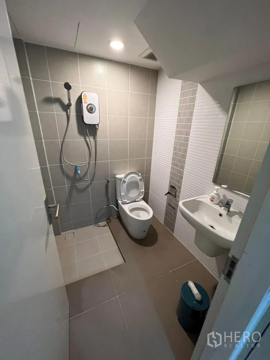Semi-detached House for rent in Saphan Sung, Bangkok - Compact bathroom with toilet, handheld shower, water heater, and wall mirror.