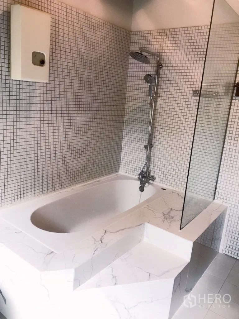 Detached House for rent in Khlong Toei, Bangkok - Close-up of marble-surround bathtub with glass screen and rainfall shower.