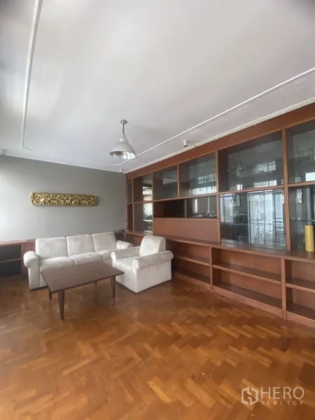 公寓 出租在Sathon, Bangkok - 客厅配白色沙发组，大型木质玻璃一体柜与吊灯。