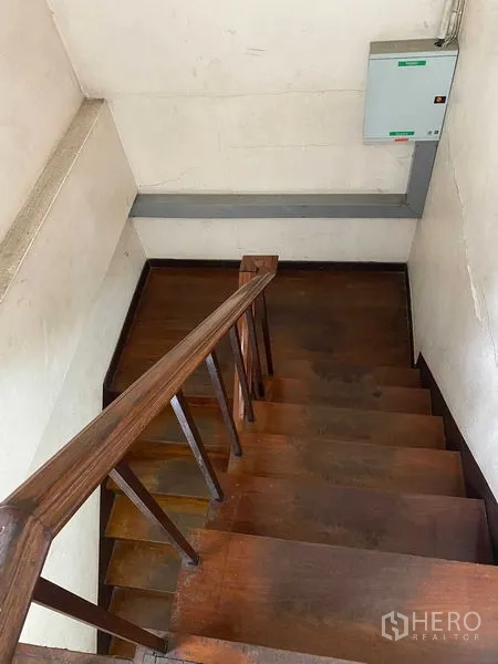 零售空间 出租在Bang Rak, Bangkok - 俯视木楼梯与扶手，墙面安装有电控箱。