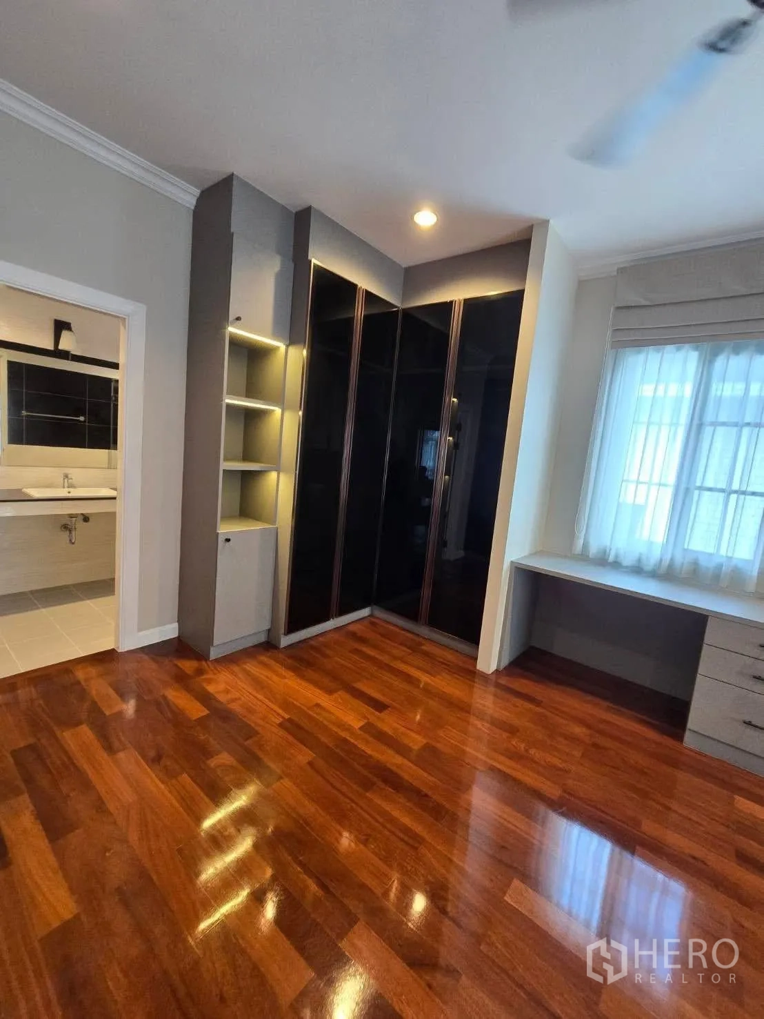 Detached House for rent in Bang Na, Bangkok - Bedroom with glossy wooden floors, built-in wardrobe, and ensuite door.