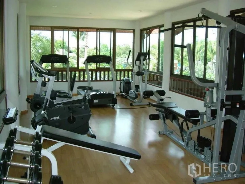 Detached House for rent in Prawet, Bangkok - Community fitness room equipped with cardio and weight machines overlooking greenery.