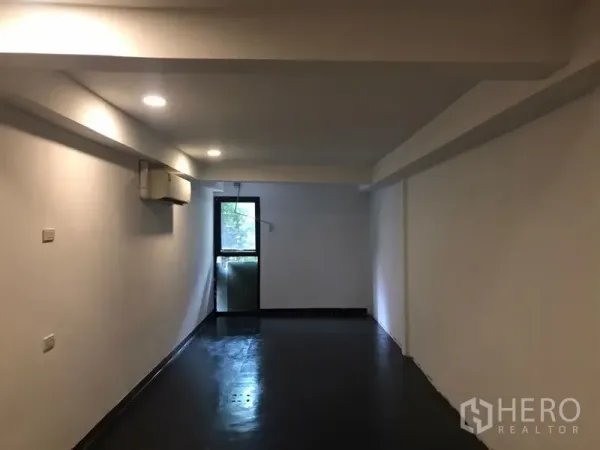 Home Office for rent or sale in Khlong Toei, Bangkok - Long workspace with recessed lighting, black floor and a glass door opening to a narrow balcony.