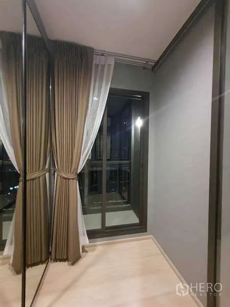 Condominium for rent - Corner space with full-height mirror wardrobe, curtains, and sliding balcony door.