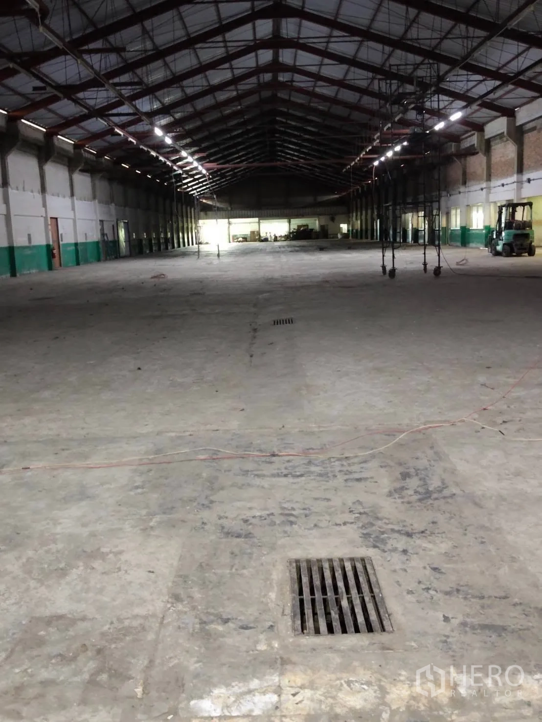 Warehouse for rent in Mueang Samut Prakan, Samut Prakan - Large warehouse interior with steel truss roof, concrete floor and floor drain.