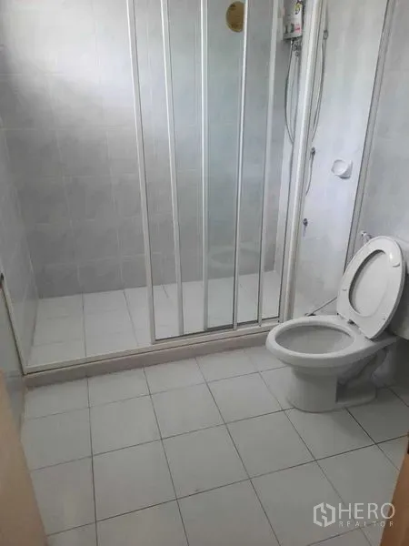 Home Office for rent in Watthana, Bangkok - Clean bathroom with glass-enclosed shower, white tiles, and toilet.