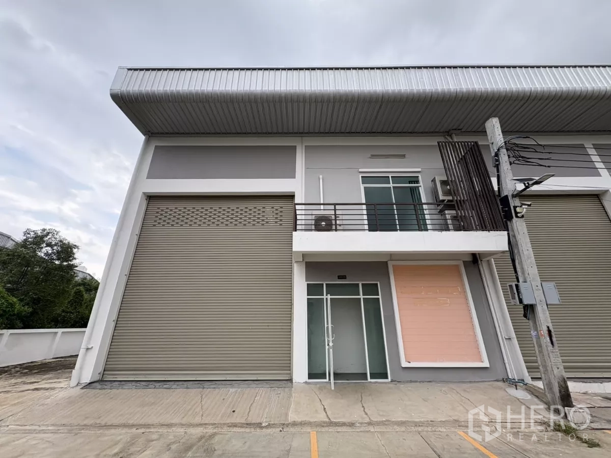 Factory for rent in Phra Samut Chedi, Samut Prakan - Modern factory facade with high roller shutters, glass entry and a balcony in Phra Samut Chedi.
