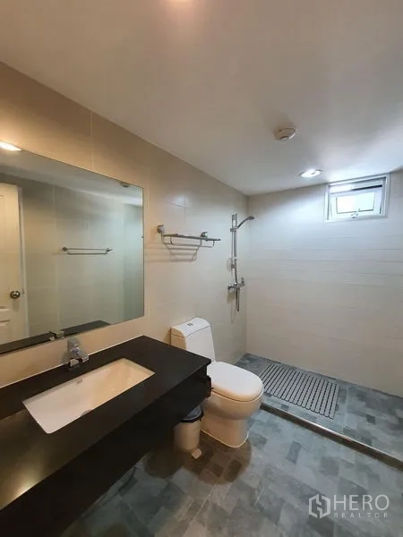 Condominium for rent in Huai Khwang, Bangkok - Modern bathroom with wide vanity, large mirror and walk-in shower with window ventilation.