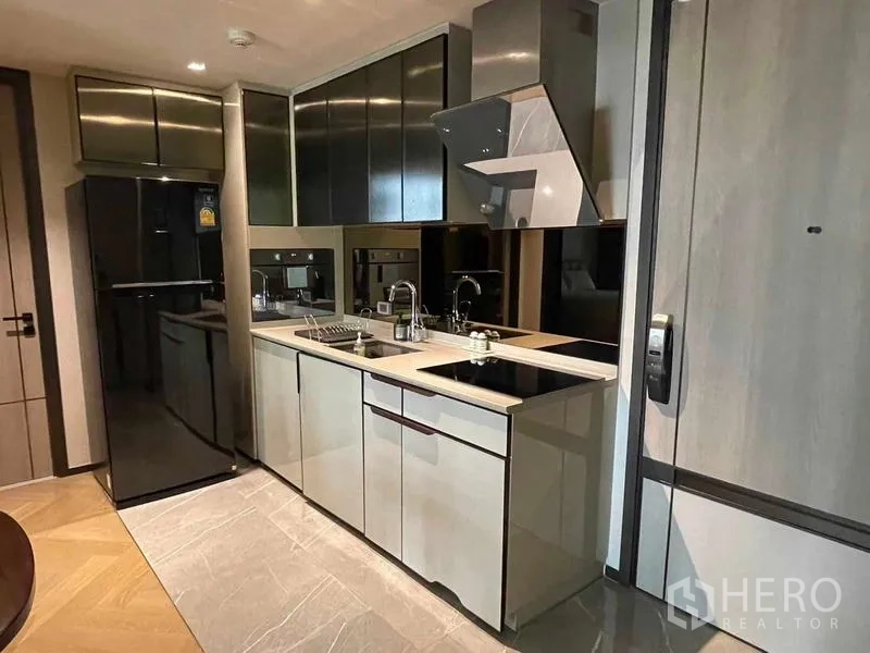 Condominium for rent - Modern galley kitchen with built-in cabinets, electric hob, hood and full-size refrigerator.
