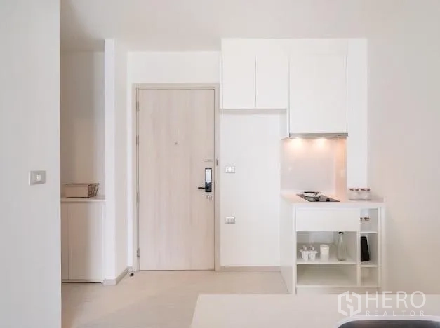 公寓 出售在Khlong Toei, Bangkok - 入口走廊配浅木色门与白色一体厨房，带灶台与柜体。