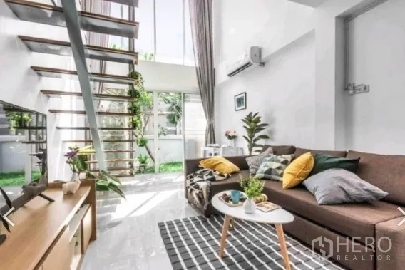 ทาวน์เฮาส์ ให้เช่าในKhlong Toei, Bangkok - ห้องนั่งเล่นโปร่งเพดานสูง โซฟามุม บันไดโปร่ง และผนังกระจกติดสวน