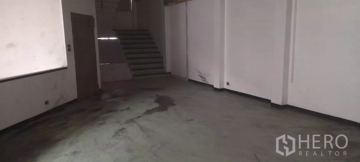 零售空间 出租在Bang Na, Bangkok - 空置零售楼层，混凝土地面与白墙，带通往上层的楼梯，待装修。