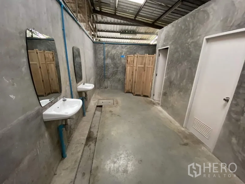 货栈 出租或出售在Khlong Luang, Pathum Thani - 工业风卫生间，混凝土墙面，双洗手池、镜子与隔间门，金属屋顶。