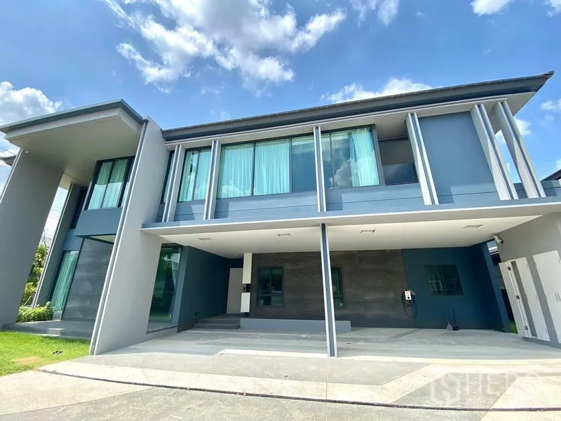 Detached House for sale in Bang Kapi, Bangkok - Modern house facade with floor-to-ceiling windows and a large covered carport.