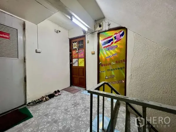 店屋 出租在Khlong Toei, Bangkok - 商铺楼层走廊，荧光灯照明，带门与指示牌，靠近楼梯口。