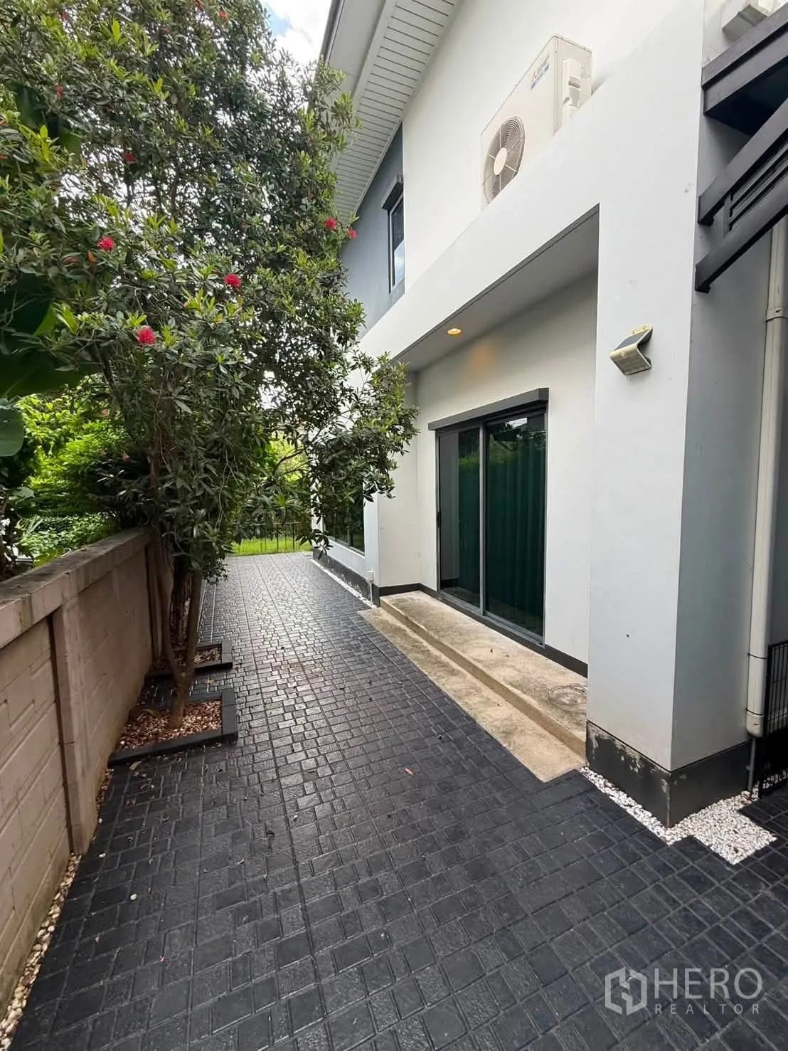 独栋房屋 for rent in Bang Kapi, Bangkok - 侧院种有树木，推拉玻璃门与铺装露台。