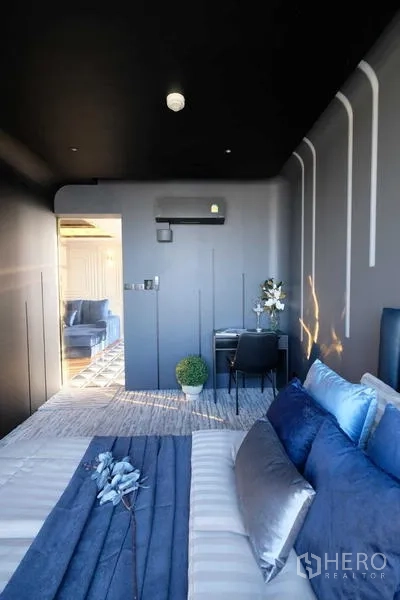 คอนโด ขาย - ห้องนอนกะทัดรัด หัวเตียงสีน้ำเงินและไฟตกแต่งบนผนัง