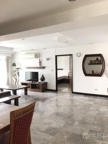 Condominium for rent in Watthana, Bangkok - Open-plan living room with TV console, wall shelves, and doorways to bedrooms.