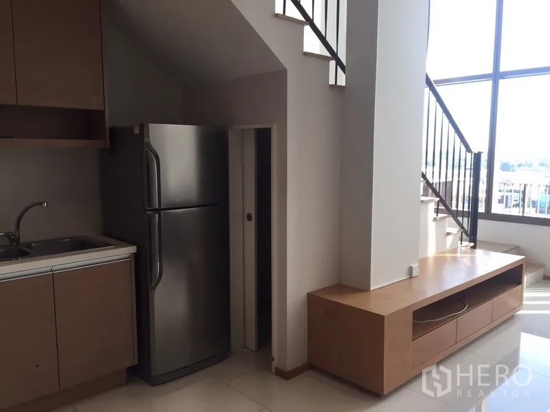 คอนโด ให้เช่าในKhlong Toei, Bangkok - มุมครัวและพื้นที่เก็บของใต้บันได ข้างชั้นวางทีวีและหน้าต่างสูง