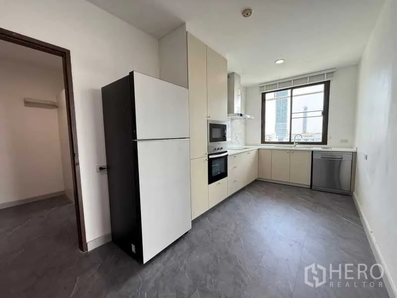 Condominium for rent - Modern separate kitchen with built-in oven, microwave, dishwasher, and a window view.