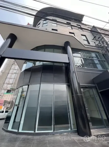 零售空间 出租在Watthana, Bangkok - 转角玻璃立面与雨棚的当代商铺外观，招牌位置显眼。