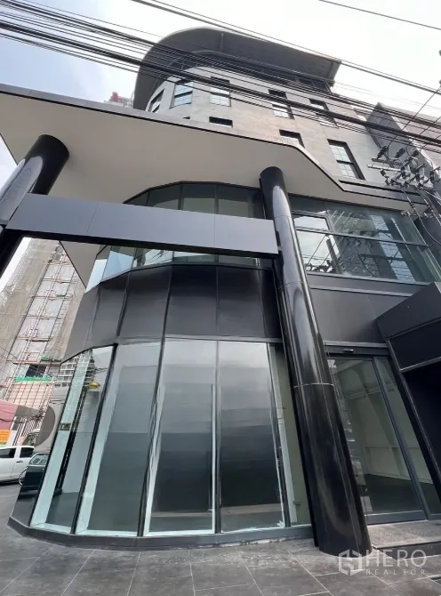 零售空间 出租在Watthana, Bangkok - 转角玻璃立面与雨棚的当代商铺外观，招牌位置显眼。