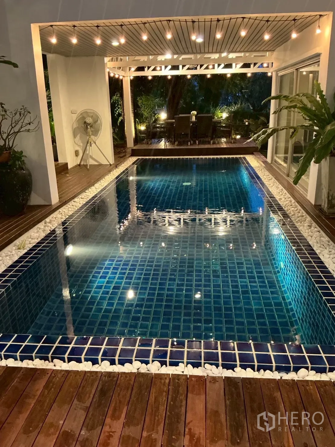 บ้านเดี่ยว for sale in Suan Luang, Bangkok - สระว่ายน้ำปูกระเบื้องสีน้ำเงินพร้อมดาดไม้และไฟระย้าตอนกลางคืน