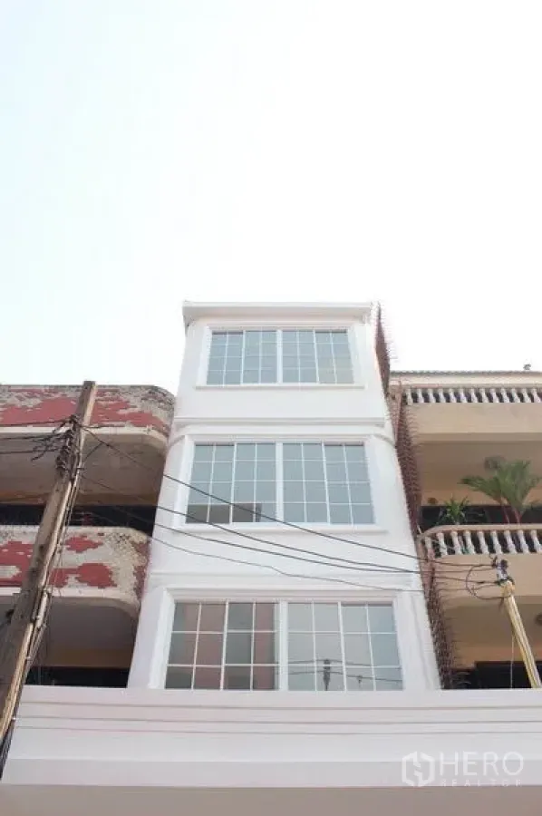 Home Office for rent in Khlong Toei, Bangkok - Freshly renovated four-storey home office facade with large grid windows between townhouses.