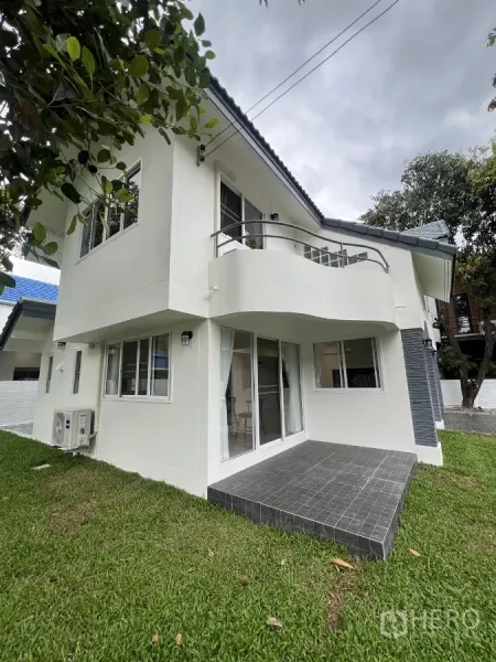 Detached House for rent in Saphan Sung, Bangkok - Corner view with sliding doors opening to a small tiled patio beneath a curved balcony.