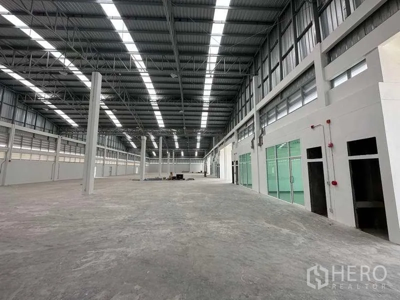 Factory for rent in Khlong Luang, Pathum Thani - Long central aisle of the factory with glass-partitioned office suites on one side.