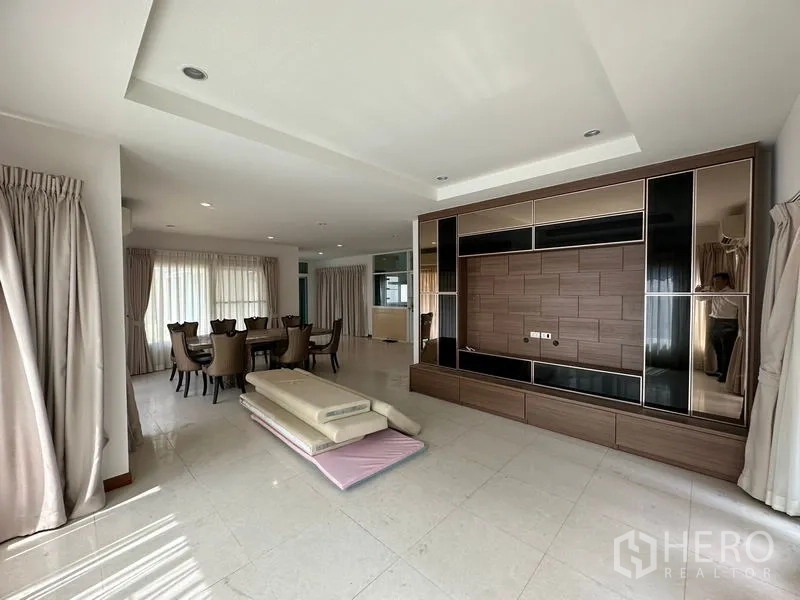 Detached House for rent or sale in Pak Kret, Nonthaburi - Living room with a large media wall and adjacent dining area.